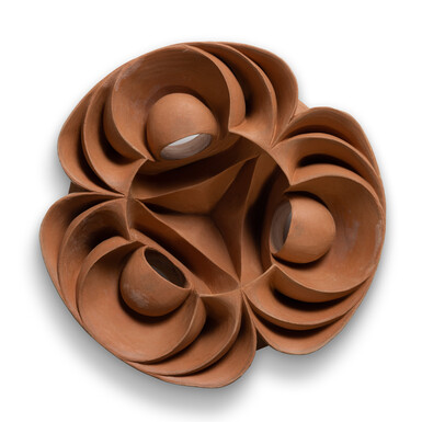A terracotta clay vessel carved in symmetrical curved waves on a white background