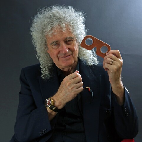 Musician and astrophysicist Brian May poses with a stereoscope lens