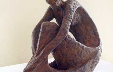 Bronze sculpture of a person sitting down and bending over