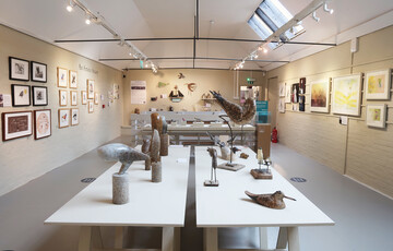 A white gallery with framed pictures and a table with sculptures