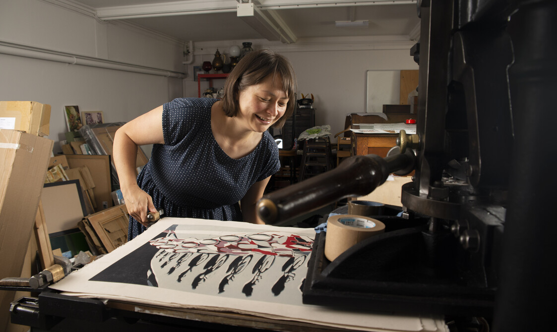 Lisa sliding a half finished print into her press in her studio