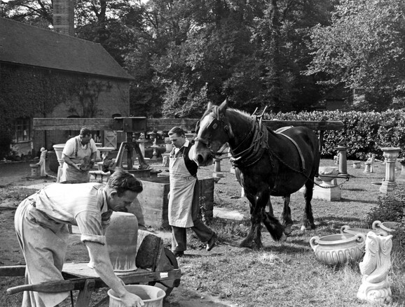 Black and white photo of pottery works, with pots and a horse