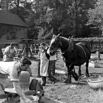 Black and white photo of pottery works, with pots and a horse