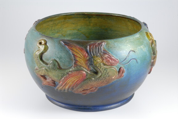 Blue and green bowl with yellow inside decorated with a red and green dragon on the outside
