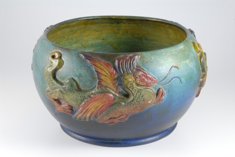 Blue and green bowl with yellow inside decorated with a red and green dragon on the outside