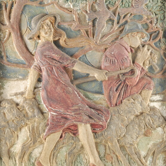 A pottery relief of a girl in a pink dress harvesting a field while a young man sits nearby