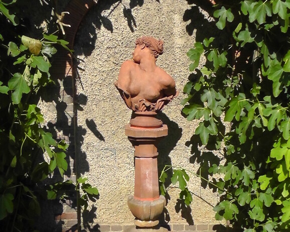Terracotta version of Clytie on a terracotta plinth in the sunken garden outside Watts Gallery
