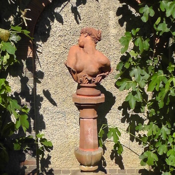 Terracotta version of Clytie on a terracotta plinth in the sunken garden outside Watts Gallery