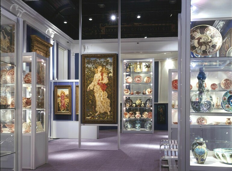 A white gallery filled with paintings and ceramics by William and Evelyn De Morgan