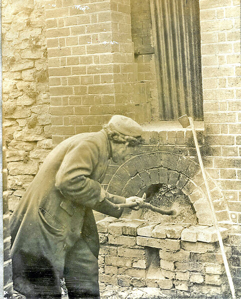 A man throws coal into a large brick kiln