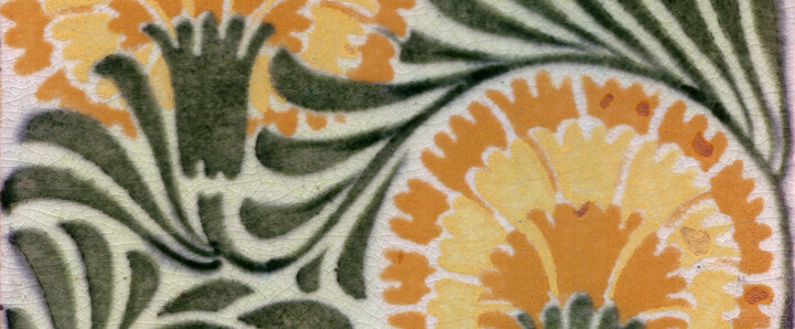 A tile with the pattern of two yellow flowers with green leaves intertwined