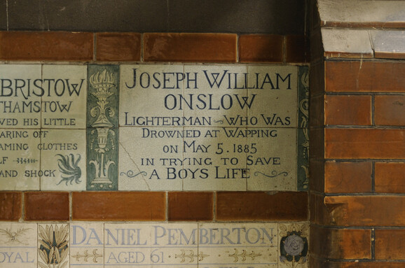A blue and white memorial tile set into a wall