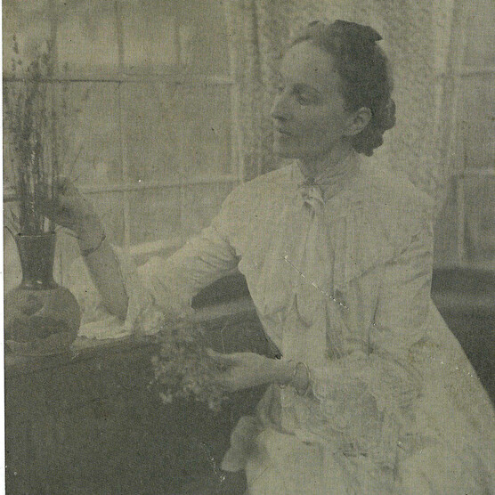 Sepia-toned portrait of a women in white by a window