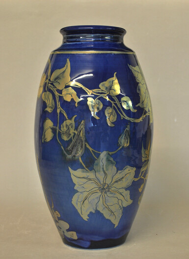 Tall blue lustreware vase with goldy-silver coloured clematis flowers around it