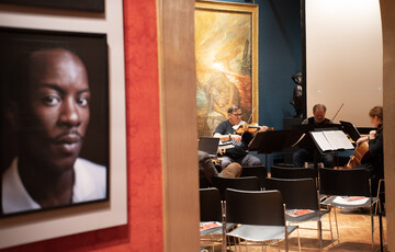 A photograph of the inside of the Historic Galleries where a quarter sit down playing the violin