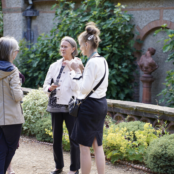 A photograph of four women stood outside the historic galleries talking and holding wine glasses