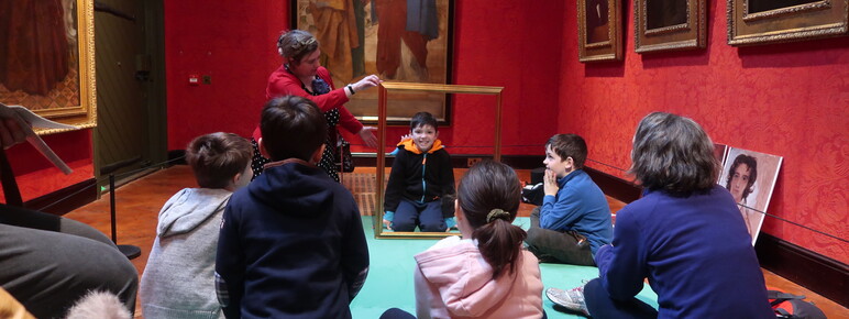 A group of families sit in the gallery listening to stories