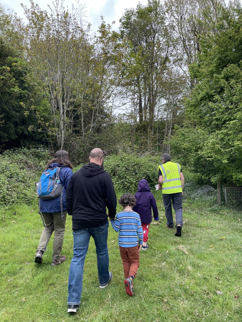 A photograph of a two men and a women with two children walking through the grounds of Watts Gallery