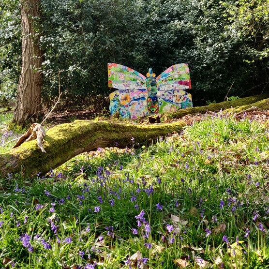 A photograph of a large man made butterfly installation in the woods of Watts Gallery