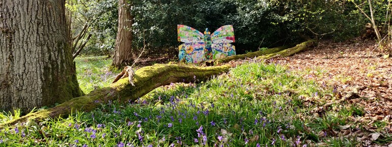 A photograph of a large man made butterfly installation in the woods of Watts Gallery