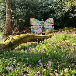 A photograph of a large man made butterfly installation in the woods of Watts Gallery