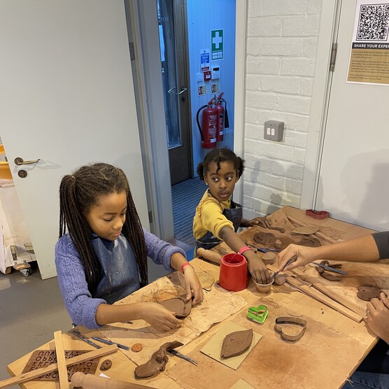 A young girl and young boy make using clay