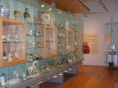 A photograph of the inside of Brighton Art Museum of a glass plinth with lots of objects inside