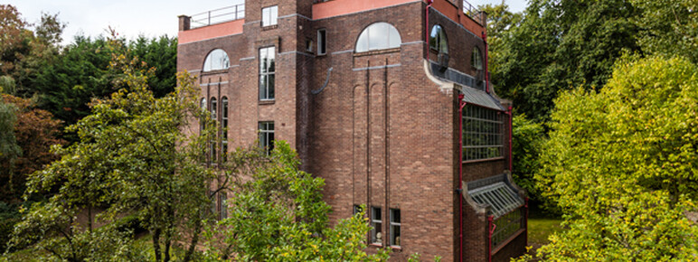 A photograph of the exterior of Dorich House Museum surrounding by tall green trees