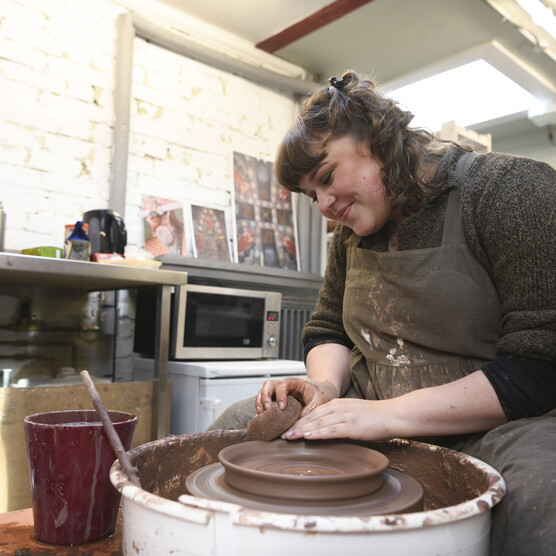 Ashleigh throws a clay dish on the pottery wheel