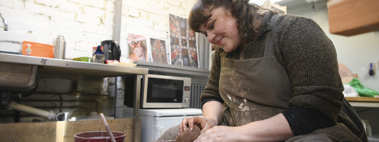 Ashleigh throws a clay dish on the pottery wheel