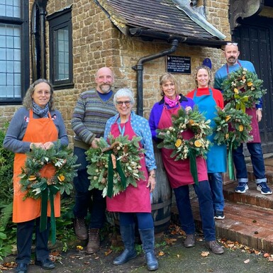 A group stand outside holding their wreaths