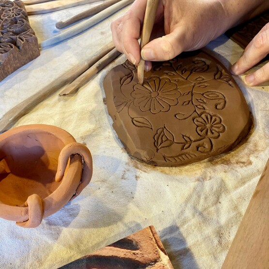 A close up photo of a woman's hand making marks on clay