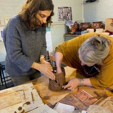 Two women working together on a ceramic piece of art