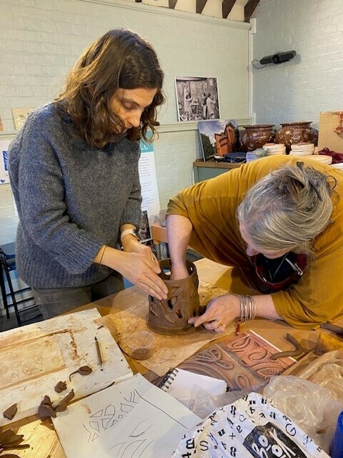 Two women working together on a ceramic piece of art