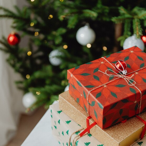 Presents wrapped up on a table in front of a Christmas tree