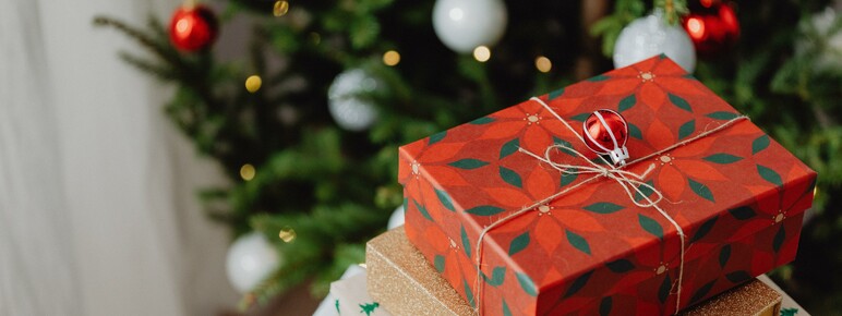 Presents wrapped up on a table in front of a Christmas tree