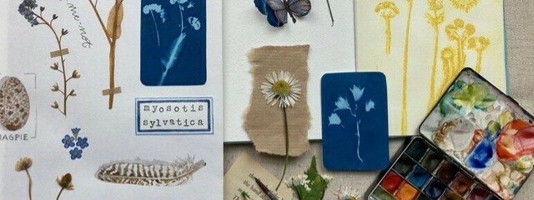 Sketchbooks, paints and paintbrushes on a table