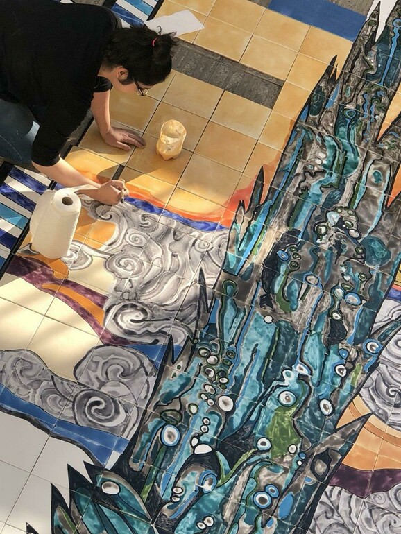 The artist Bahareh Khomeiry working painting a colourful ceramic mural