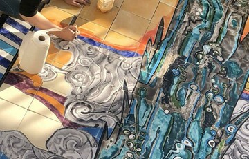 The artist Bahareh Khomeiry working painting a colourful ceramic mural