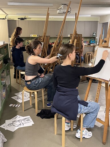 A photo of a group of young people sitting in a class drawing