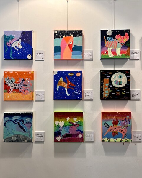 Square paintings by children hung on wall