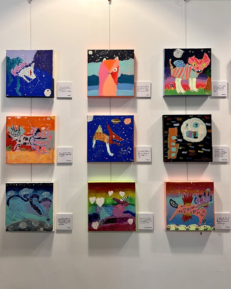 Square paintings by children hung on wall
