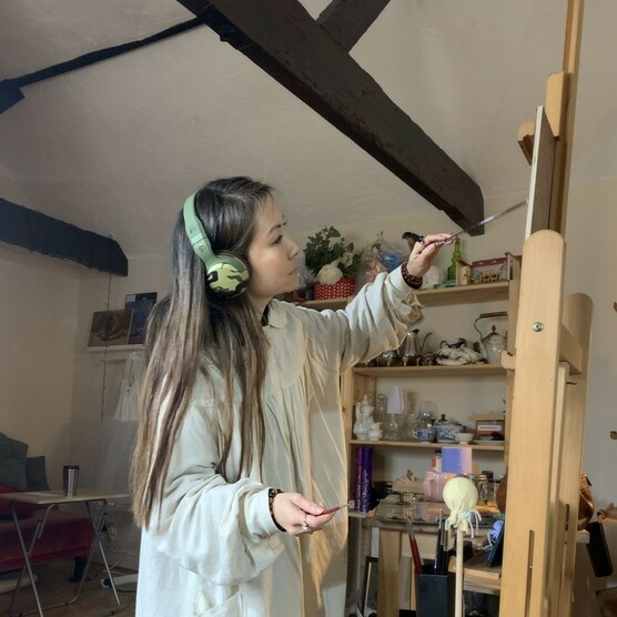 Sarah paints on an easel