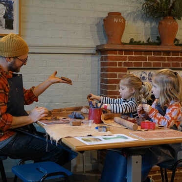 Father with two daughters sitting at a table doing pottery