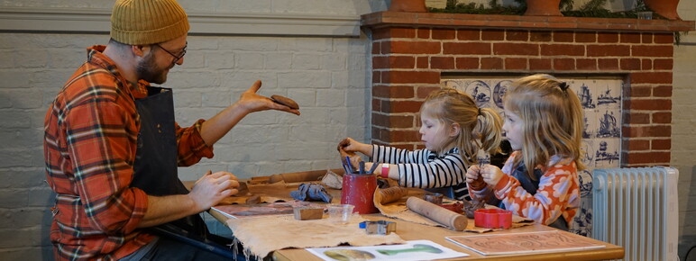 Father with two daughters sitting at a table doing pottery