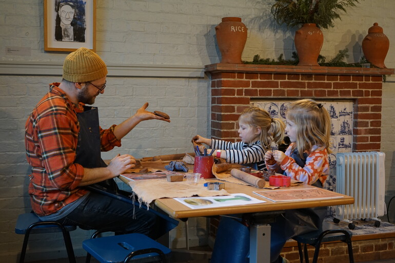 Father with two daughters sitting at a table doing pottery