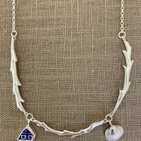 Photo of a silver necklace that looks like a flower stem, with a seashell and gem charm