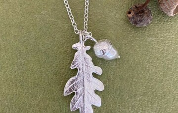 Photo of a silver necklace with an oak leaf and acorn charm