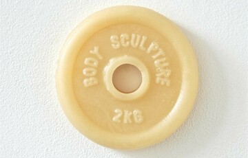 Photo of a light yellow sculpture which resembles a weight