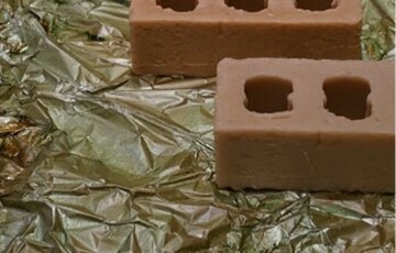 Photo of some bricks laid on the ground on top of green plastic tarp